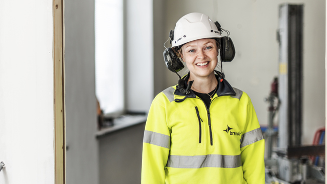 Leende ung elektriker på ett bygge